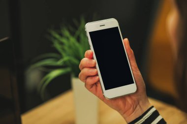İşkadını beyaz smartphone içinde boş ekran bakıyor