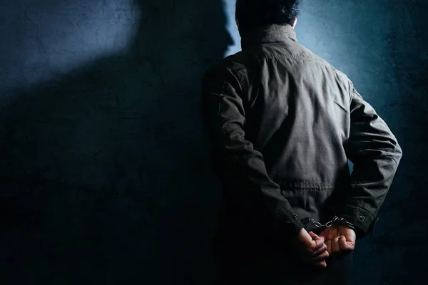 Homem preso criminoso com algemas de frente para o muro da prisão — Fotografia de Stock
