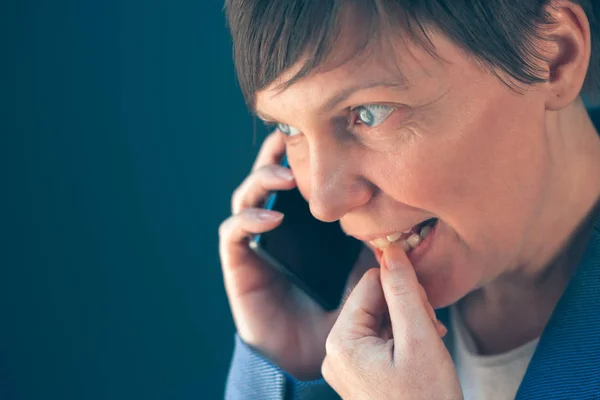 Нервная деловая женщина грызет ногти во время телефонных переговоров — стоковое фото