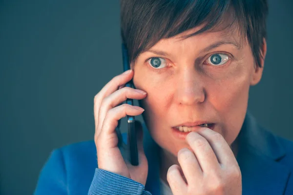 Nerviosa mujer de negocios muerde las uñas durante conversiones telefónicas —  Fotos de Stock