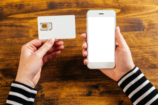 Жінка тримає смартфон і нову SIM-карту — стокове фото