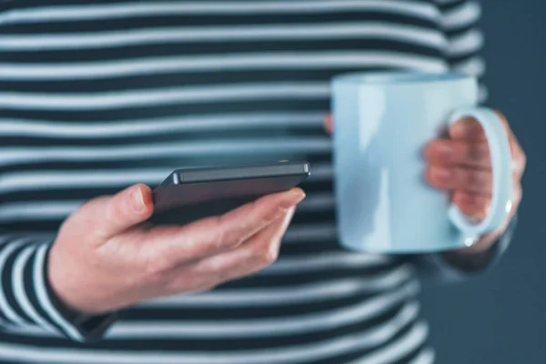 Femme buvant du café et lisant des SMS sur téléphone portable — Photo