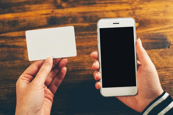 Woman holding blank business card and mobile phone — Stock Photo, Image