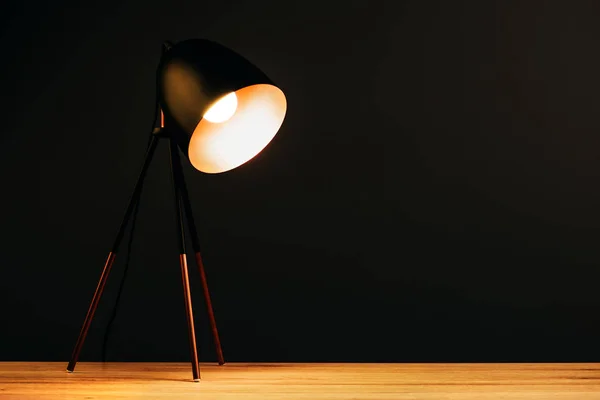 Настольная лампа на столе в темном кабинете — стоковое фото