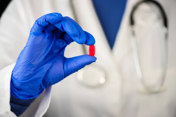 赤タブレット錠剤を提供している女性医師 — ストック写真