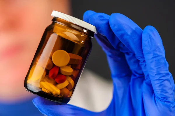 Female doctor holding unlabeled bottle of various pills and medi — Stock Photo, Image