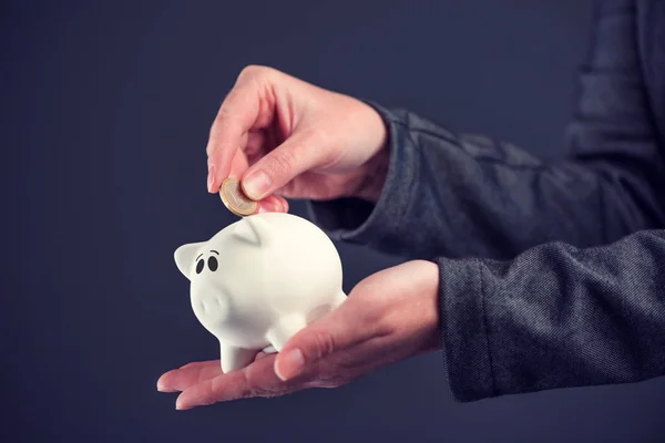 Zakenvrouw een euromunt aanbrengend piggy bank — Stockfoto