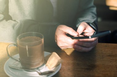 Cep telefonu kullaranarak ve kafede sıcak çikolata içme kadın