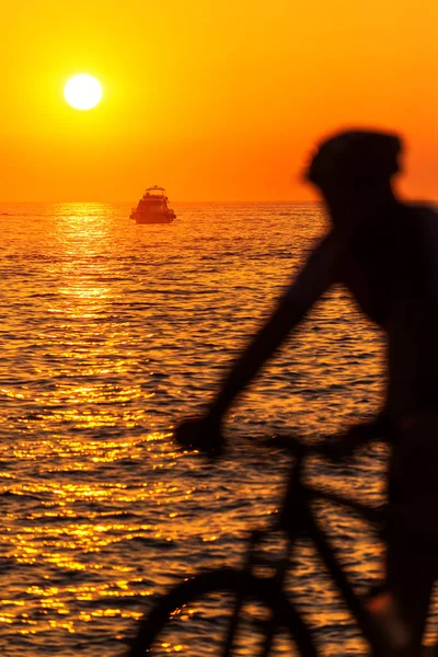 Bewegungsunschärfe Silhouette eines männlichen Bikers am Meer bei Sonnenuntergang — Stockfoto