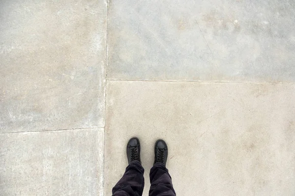 Man die op betonnen vloer oppervlak, voeten van bovenaf — Stockfoto