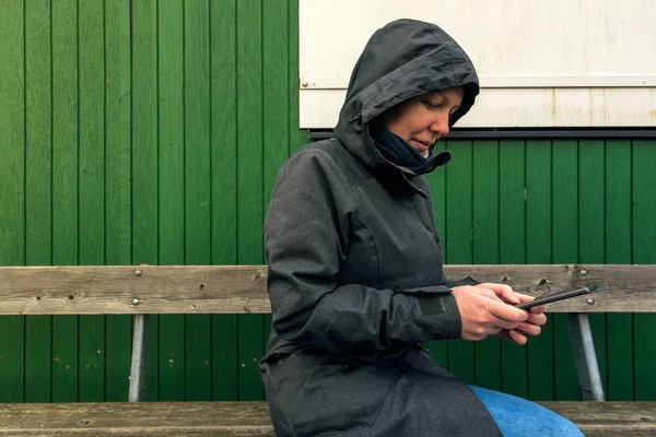Mulher autêntica no inverno jaqueta digitando mensagem sms ao ar livre — Fotografia de Stock