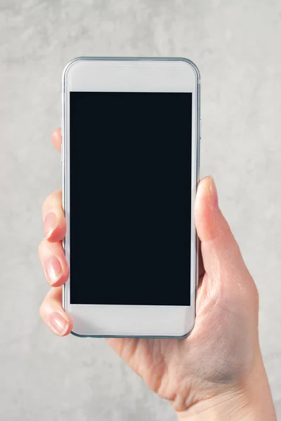 Mano femenina sosteniendo el teléfono móvil con pantalla en blanco simulada —  Fotos de Stock