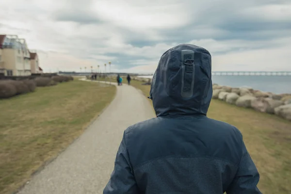 Одинокая женщина в капюшоне сзади, стоящая на берегу моря — стоковое фото