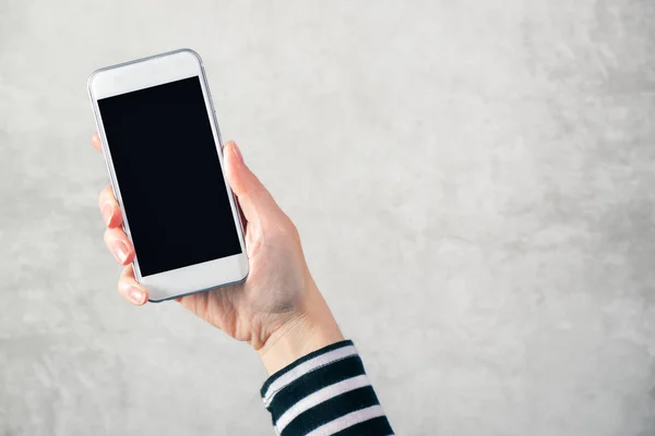 Mano femenina sosteniendo el teléfono móvil con pantalla en blanco simulada —  Fotos de Stock