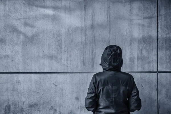 K nepoznání s kapucí ženská osoba čelí betonová zeď jako pojištěnec — Stock fotografie