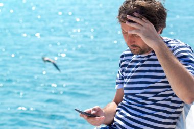 Cep telefonuyla deniz kenarında yaz tatilde erkek turist