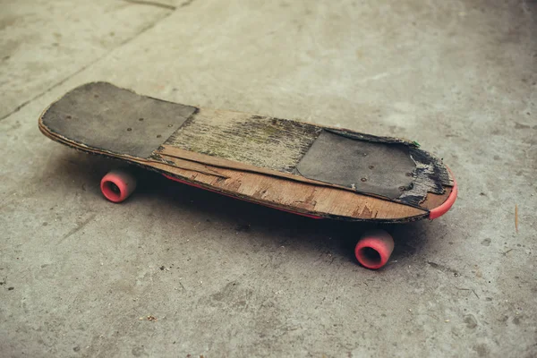 Gammelt forvitret skateboard på betonoverflade - Stock-foto
