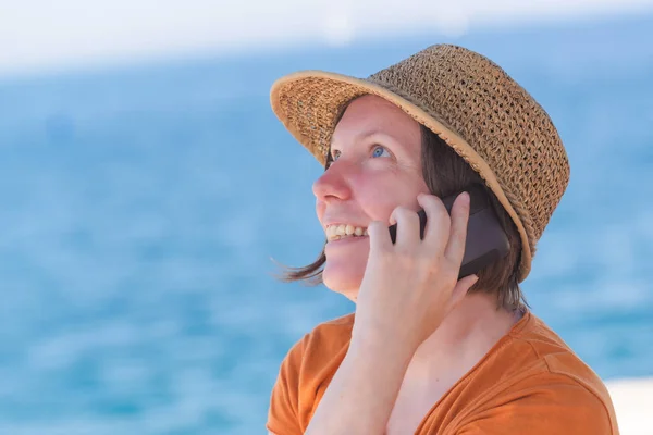 Красивая взрослая кавказка с мобильного телефона на берегу моря — стоковое фото