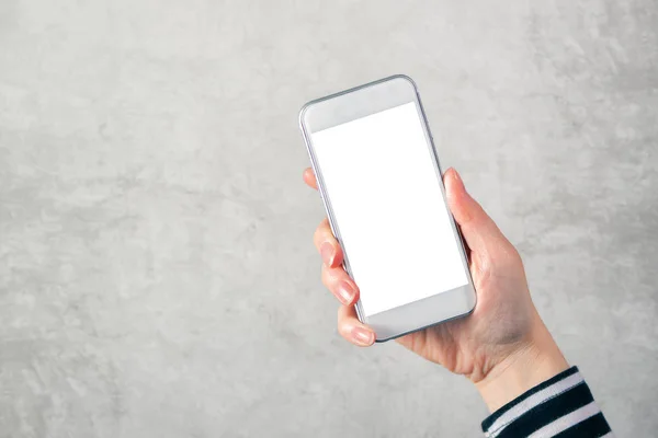 Main féminine tenant téléphone portable avec écran blanc maquette — Photo