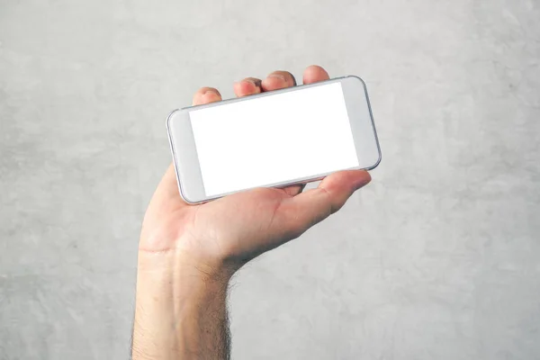 Męskiej ręki trzymającej telefon komórkowy z udawanym pusty ekran — Zdjęcie stockowe