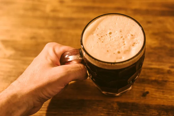 Homem bebendo cerveja escura na caneca de cerveja de vidro ondulada britânica — Fotografia de Stock