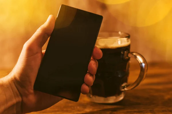 Man med mobil och mörkt öl mugg — Stockfoto