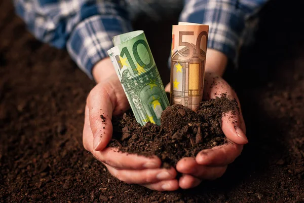 Hands with fertile soil and euro money banknotes — Stock Photo, Image