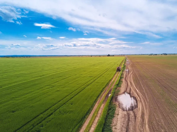 Tractor en la carretera del campo a través del campo de trigo, drone pov — Foto de Stock