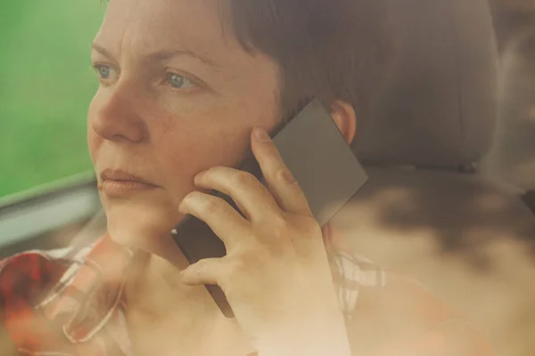 Worried woman talking on mobile phone in car — Stock Photo, Image