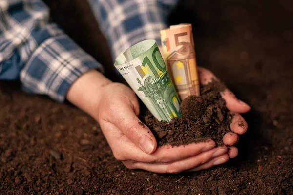 Mãos com solo fértil e notas de euro — Fotografia de Stock