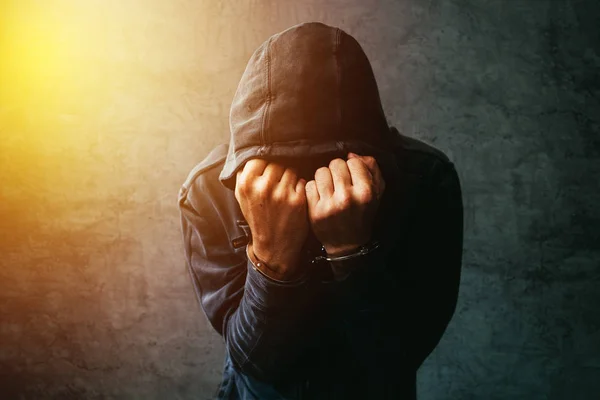 Arrested computer hacker with handcuffs wearing hooded jacket — Stock Photo, Image