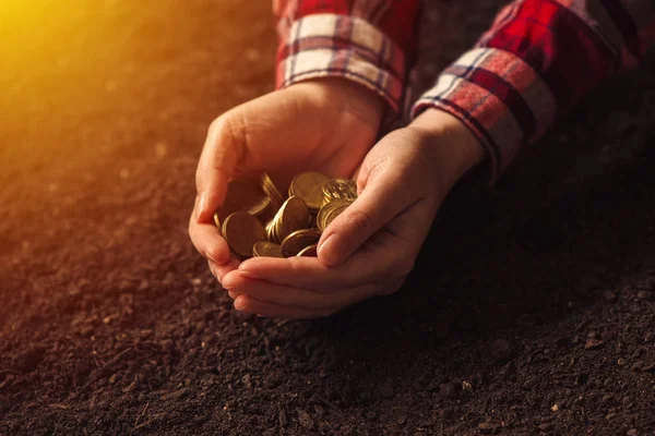 Farmer with handful of coins over soil land — Stock Photo, Image