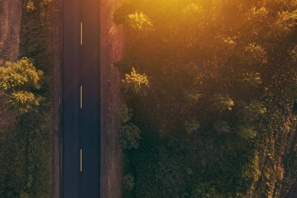 Estrada vazia através do campo ao pôr do sol, vista aérea drone pov — Fotografia de Stock