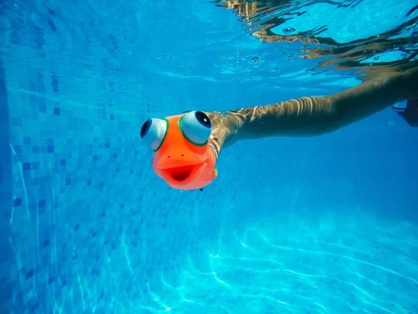Jeu d'enfant avec un jouet de poisson en caoutchouc générique dans la piscine — Photo