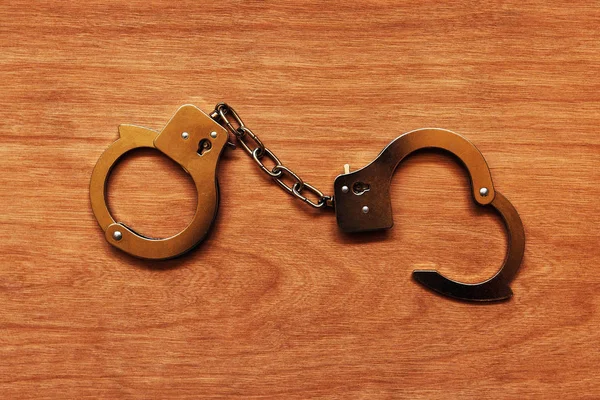 Handcuffs on wooden background — Stock Photo, Image
