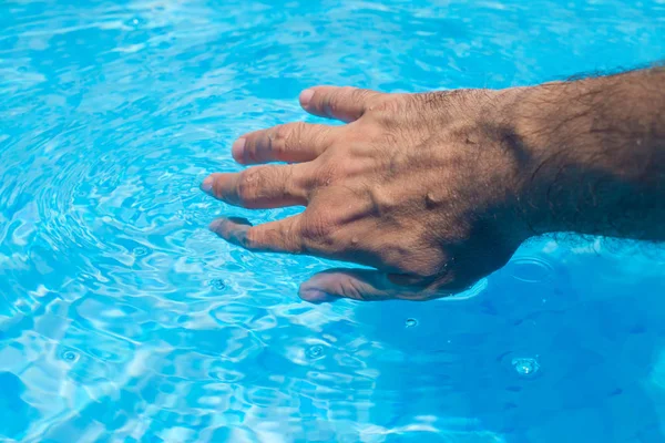 Mannenhand raken duidelijk zwembadwater — Stockfoto