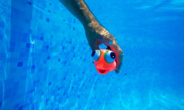 Hombre jugando con el juguete genérico de goma de pescado en la piscina —  Fotos de Stock