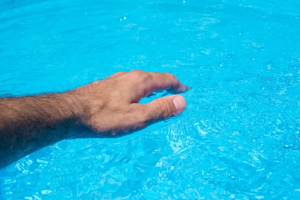 Mannenhand raken duidelijk zwembadwater — Stockfoto