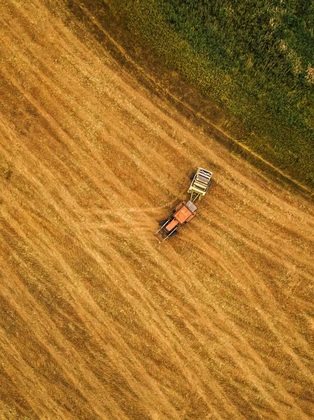 Luftaufnahme eines Traktors, der Heuballen auf einem Feld rollt — Stockfoto