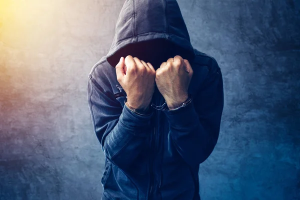 Arrested computer hacker with handcuffs wearing hooded jacket — Stock Photo, Image