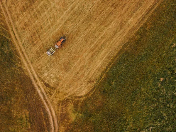 Luftaufnahme eines Traktors, der Heuballen auf einem Feld rollt — Stockfoto