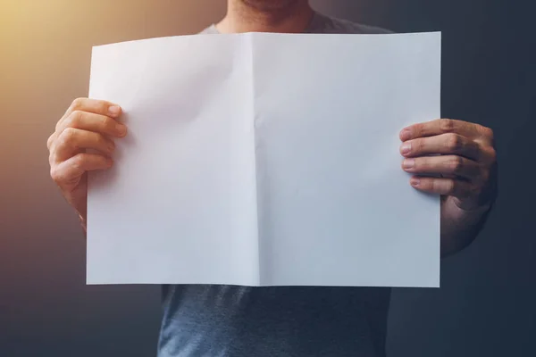 Hombre casual sosteniendo papel A3 en blanco extendido como espacio de copia —  Fotos de Stock