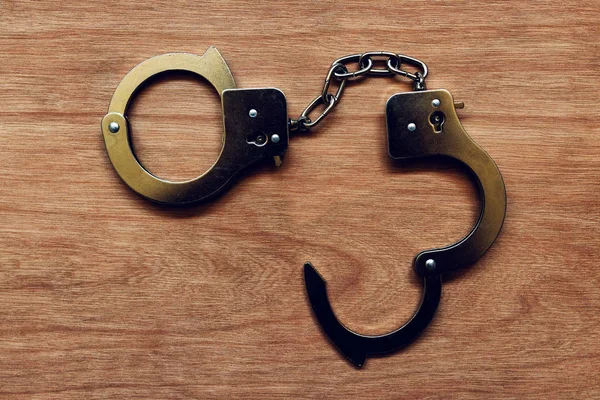 Handcuffs on wooden background — Stock Photo, Image