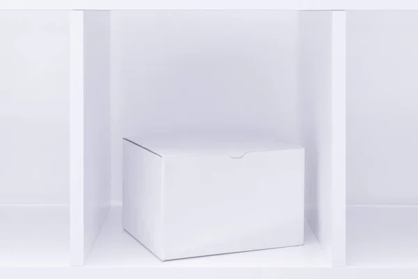 Коробка из белого картона на деревянной полке в качестве места для копирования — стоковое фото