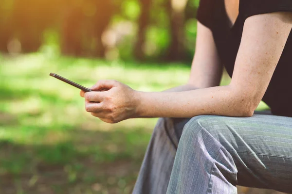 Mulher usando smartphone no parque público — Fotografia de Stock