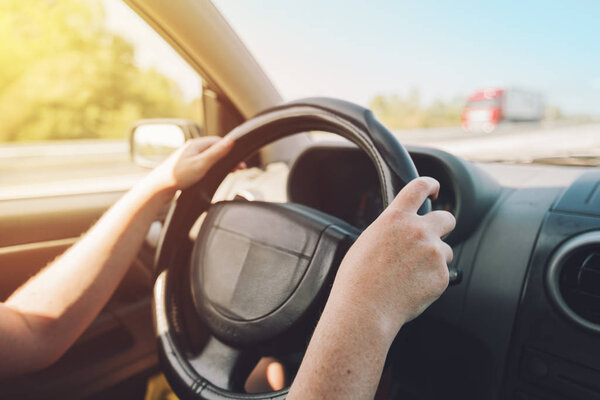 Woman holding on black steering wheel