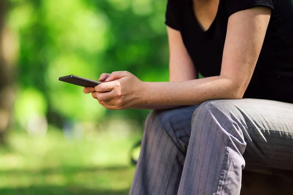 Frau benutzt Smartphone in öffentlichem Park — Stockfoto