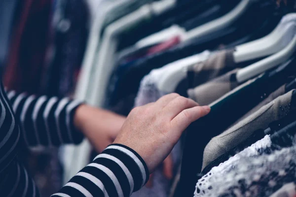 Mujer navegando a través de la ropa en el mercado de segunda mano — Foto de Stock