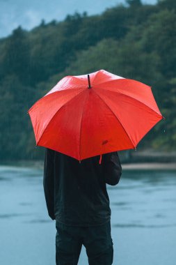 Yağmur Adam kırmızı şemsiye ile contemplates