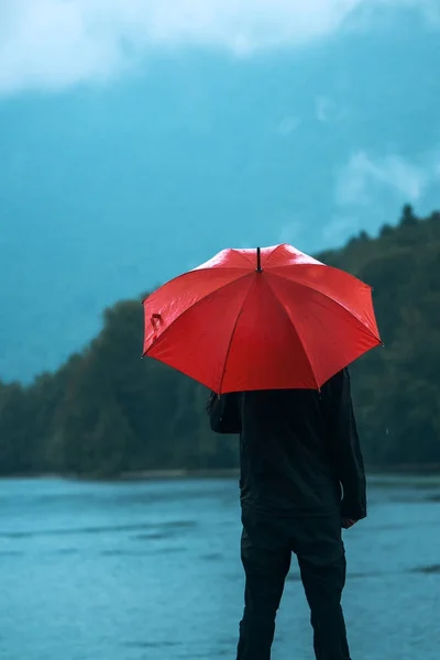 Mann mit rotem Regenschirm denkt über Regen nach — Stockfoto